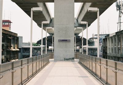 Empty walkway leading towards buildings in city