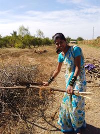 Portrait of woman cutting branches on land against sky