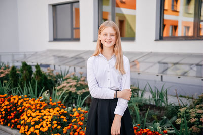 Portrait of young woman standing against building