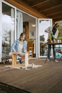 Young woman making furniture with man doing gardening on porch