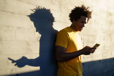 Shadow of man holding mobile phone while standing on wall