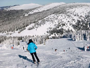 Rear view of woman skiing on snowcapped mountain