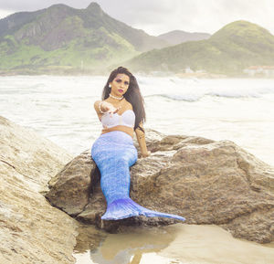 Portrait of young woman on rock at beach