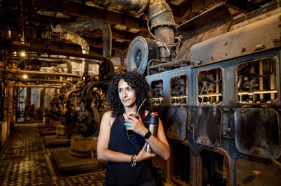 Portrait of a mixed race woman smiling while posing inside an abandoned factory.