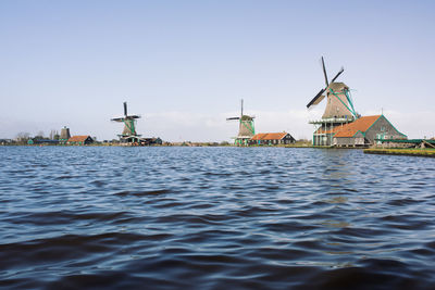 Traditional windmill by water against sky