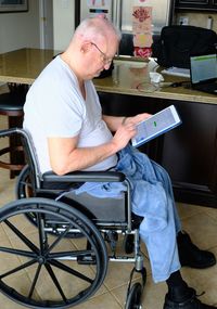 Senior man using digital tablet while sitting on wheelchair