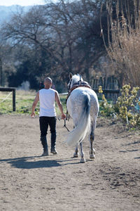 Full length of man walking with horse against sky