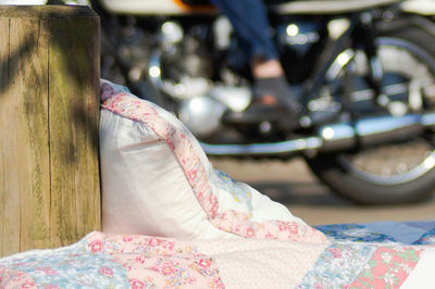 Close-up of pillows by wooden post against motorcycle