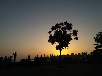 Silhouette people against clear sky during sunset