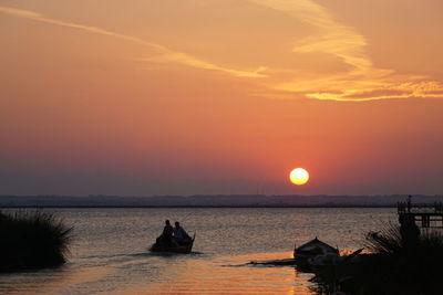 Silhouette boat in sea against sky during sunset