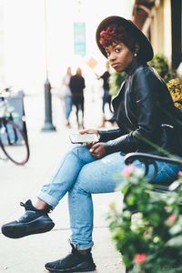 Young woman using phone while sitting on camera