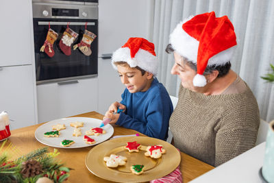High angle view of grandmother and granddaughter preparing cookies at home