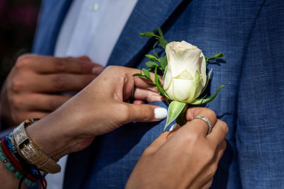 Close-up of hands attaching rose on blazer