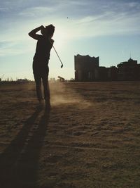 Rear view of man playing golf at dusk