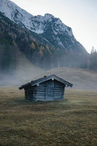 Built structure on field by mountain against sky