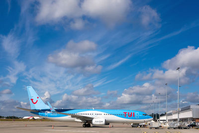 Airplane flying over airport runway against sky