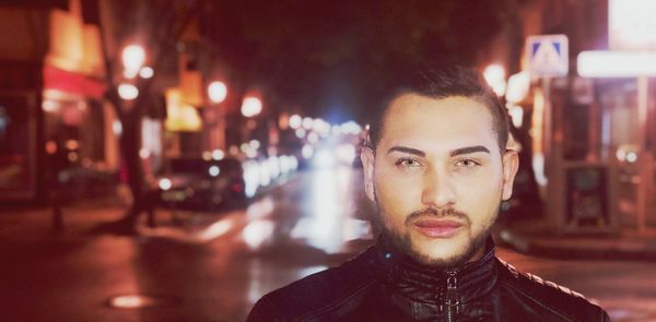 Portrait of young man in city at night