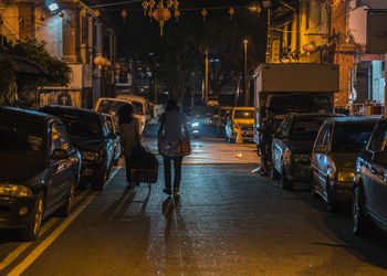 Rear view of people on illuminated street at night