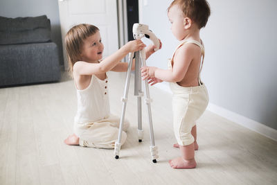 Cute kids siblings understand looking at tripod at home in bright interior