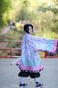 Portrait of woman standing against tree