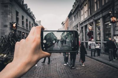 Close-up of person hand photographing using smart phone on street