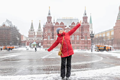 Full length of woman standing on snow covered city