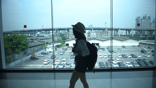 Rear view of woman looking through glass window