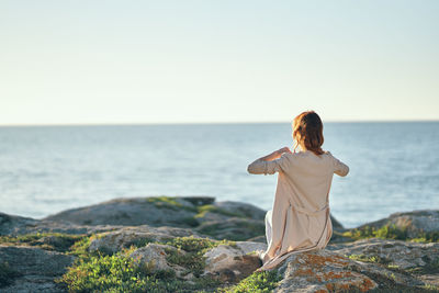 Rear view of man looking at sea against sky