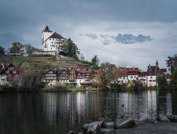 Buildings by river against sky