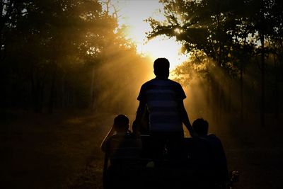 Silhouette people against trees during sunset