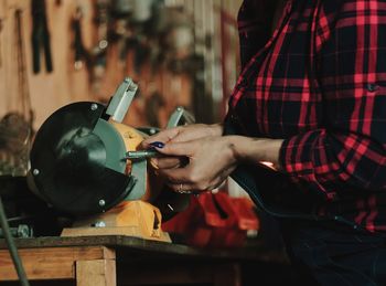 Midsection of woman using machinery in workshop