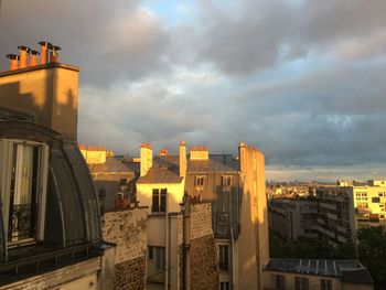 Buildings in city against cloudy sky