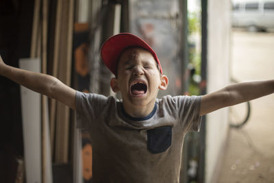 Portrait of boy with arms raised outdoors