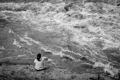 Rear view of woman sitting on sea shore