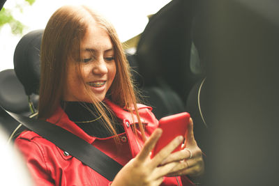 Trendy girl sitting in a car. smiling teen using smartphone chat with friend woman enjoy free time