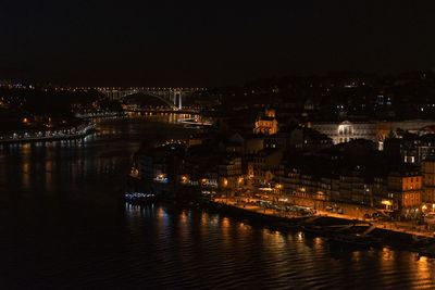 Illuminated bridge over river against sky at night