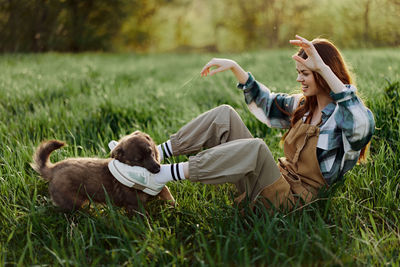 Smiling young woman with dog lying on grass