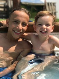 Portrait of happy brothers swimming in pool