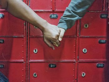 Close up of two person hand holding together in front of mailbox