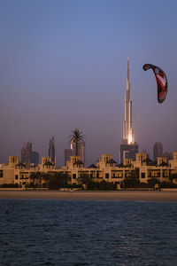 Sea by buildings against clear sky