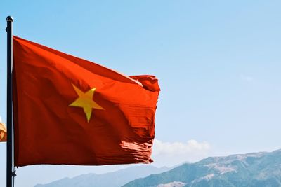 Low angle view of red flag on mountain against sky