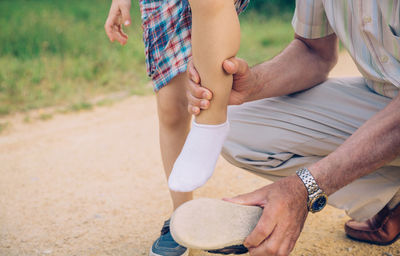 Low section of grandfather helping grandson to remove shoe