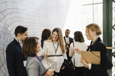 Smiling male and female professional discussing while standing at convention center