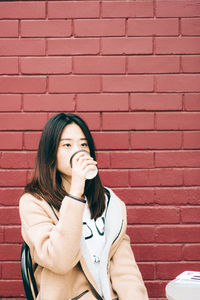 Portrait of woman against brick wall