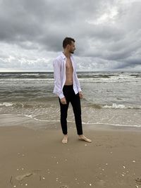 Full length of man standing on beach against sky