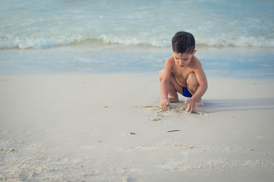 Full length of shirtless boy on beach