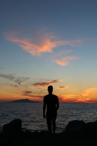 Rear view of silhouette man standing on beach during sunset