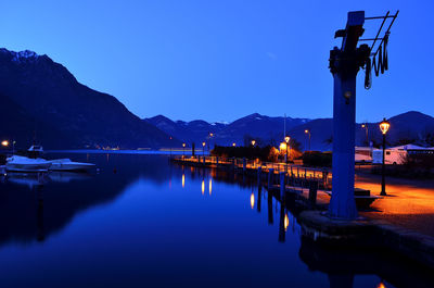 Illuminated bridge against blue sky at night