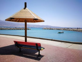 Chair on beach against clear sky