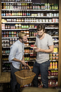 Young male friends reading label against shelf in supermarket